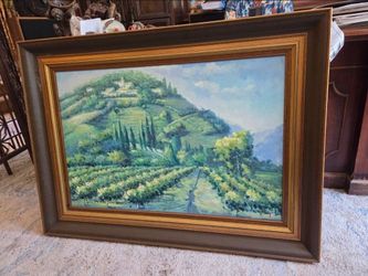 The painting depicts a landscape of Tuscan vineyards and features a gold and brown frame.