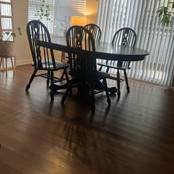 Black dining table with four chairs and leaf