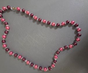 a hand-strung beaded pearl necklace featuring alternating warm metallic colors and clear accent spacers.