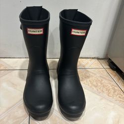 Black rubber rain boots from Hunter. These boots have an adjustable buckle strap on the back and are a mid-calf height. Size US 7, UK 5, EU 38.