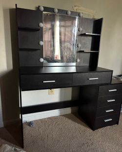 black vanity desk with a lighted mirror, often used as a makeup or dressing table.