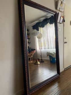 Large full-length mirror with decorative dark wood frame.