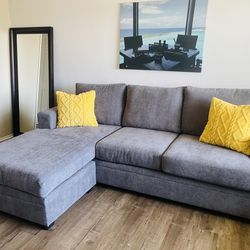 Sofá reversible color Grey Living Spaces   Bonaterra Charcoal Grey Fabric 97" Sofa with Reversible Chaise