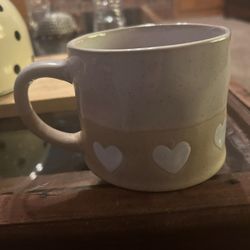 Hearts Hand Painted coffee mug by Prima Design.  It is made of ceramic and is dishwasher and microwave safe. The mug features a two-tone design with a