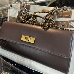 Steve Madden structured shoulder bag features a brown faux leather finish with a unique gold-tone lock closure