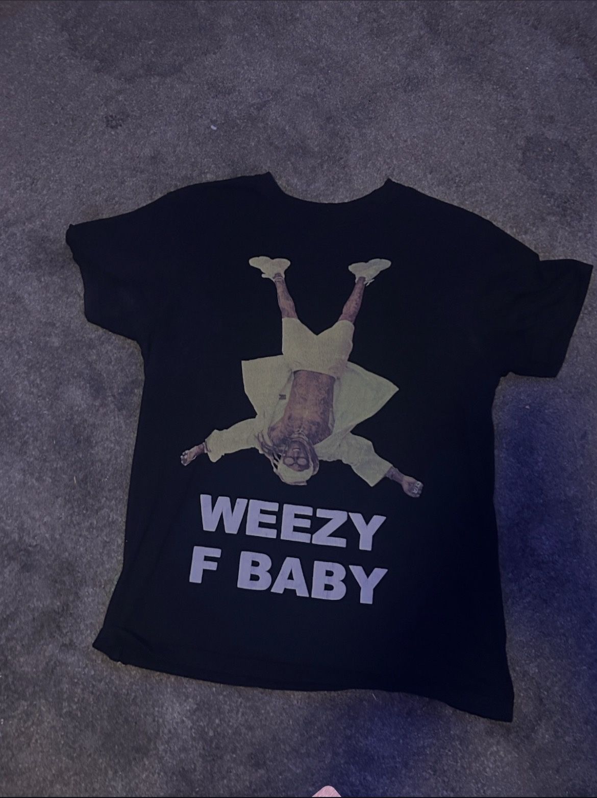Black short-sleeve graphic T-shirt featuring a bold “WEEZY F BABY” print with a full-body graphic design. Classic crew neck with a relaxed, everyday f