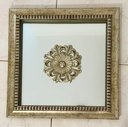 Decorative wall mirror with medallion in the center.