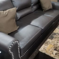 Dark brown faux leather sofa and loveseat with pinheads