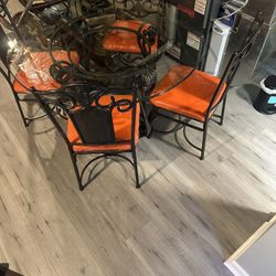 Beautiful Wrought Iron  & round glass dining table with 4 orange newly upholstered seats.