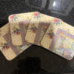 Set of four MacKenzie-Childs style decorative coasters with floral and map designs.