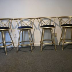 Gold metal bar stools with navy blue velvet seats.