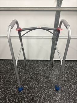 WALKER silver aluminum two-button folding mobility walker equipped with 5-inch front wheels and rear glide caps/balls, designed to provide stability a