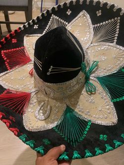 Ornate black velvet sombrero with silver, red, and green embroidery. This hat has a wide brim decorated with sequins and intricate thread work. The in