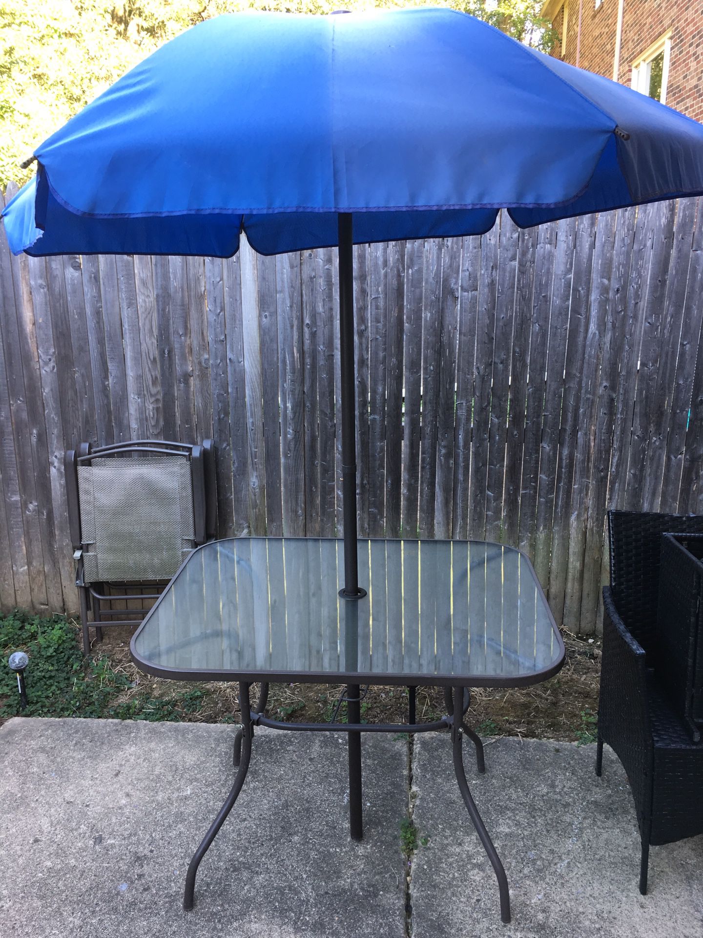 Glass patio table with 2 folding chairs and umbrella