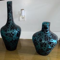 This is a set of two teal cameo glass vases, likely sand-carved with a floral or vine pattern.