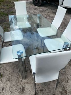 Modern glass dining table with six white chairs.some rips on chairs $95 Located Mount Dora Fla 32757