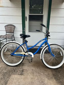 blue Huffy Cranbrook women's cruiser bike featuring a single-speed drivetrain white fenders