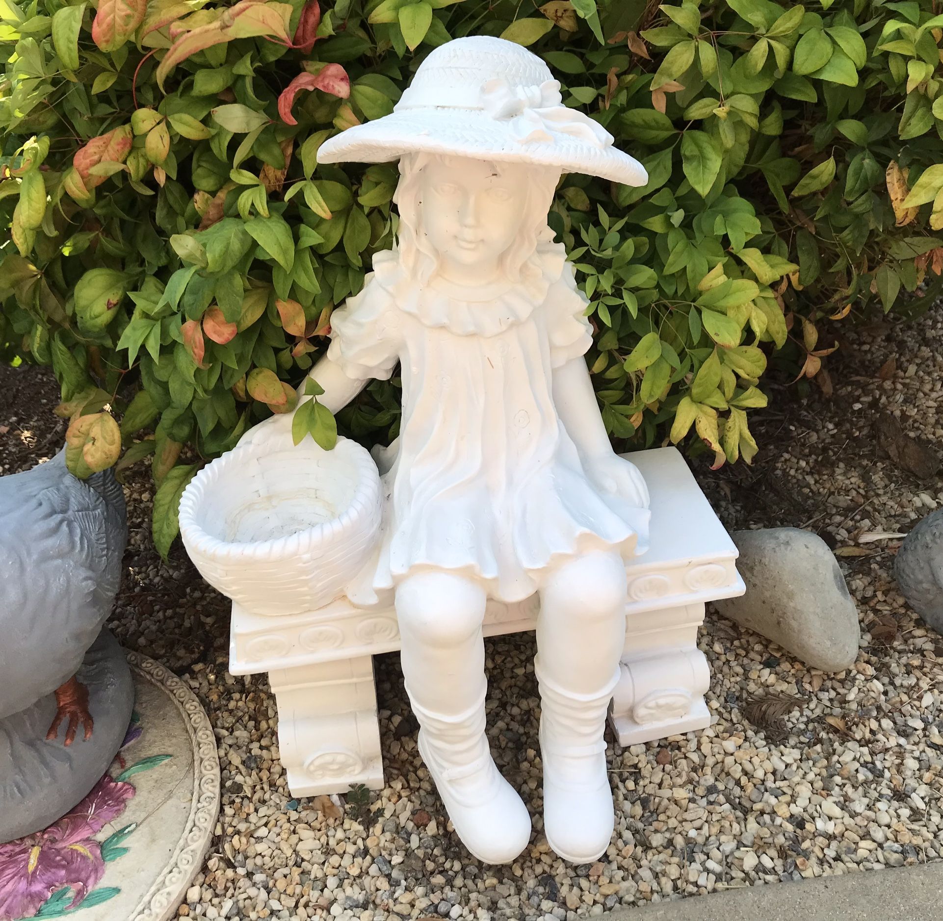 Beautiful girl with basket sitting on bench garden statue