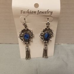 Ornate silver-tone filigree frames hold faceted blue crystals. 