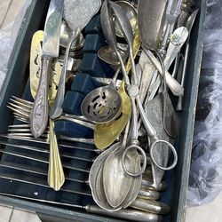 a collection of vintage silver-plated serving utensils and flatware, likely from various antique sets.  The assortment includes decorative items such 