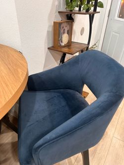 Stylish round wood dining table with black metal base. Comes with four comfy blue velvet chairs.