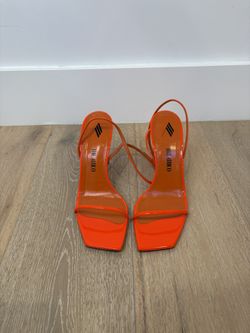 The Attico Ankle Strap Sandals in a neon orange color
