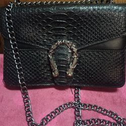 Black Flaux Leather Snake Print Cross Body Bag With A Chain Strao And A Horse Bit Style Buckle For Sale.