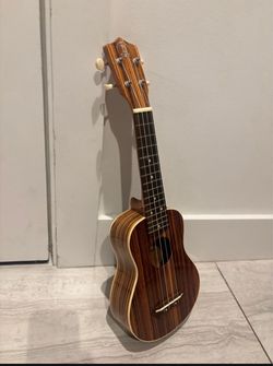 Tycoon Percussion Zebrano Ukulele (Model number IQ-W072-03), which is branded under their "Coco" line of acoustic strings. 21” includes case $75