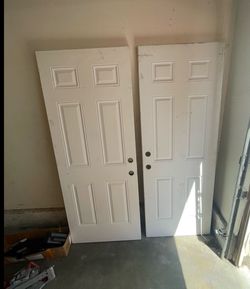 White 6-panel interior doors are made of wood or composite material. Each door has pre-drilled holes for a handle and a deadbolt. The surface is paint