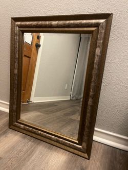 Rectangular wall mirror with an ornate, wide antique gold or distressed bronze-toned wooden frame