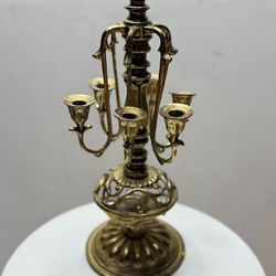 An exquisite tabletop candelabrum in the classical style. A highly detailed piece: featuring sculpted arms, an openwork base, and a decorative finial.