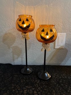 Glass jack-o’-lantern candle holders on metal base