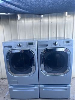 Gray LG washer and gas dryer set with pedestals.