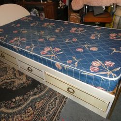 Twin size bed with drawers and mattress.