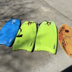 3 boogie boards and a skimboard 