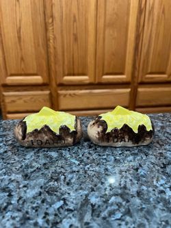 Vintage Ceramic Idaho Baked Potato Butter Pair of Salt  and Pepper Shakers.  Size appropriately 3 1/2 inches long.  Preowned.  On one shaker the top O