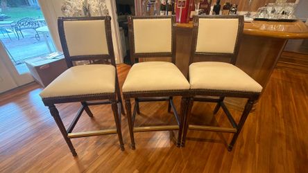 Add timeless elegance to your kitchen or home bar with this beautiful set of three upholstered counter stools. Each stool features a solid dark wood f