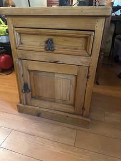rustic, country-style solid pine nightstand or bedside cabinet featuring a single top drawer, a lower cabinet door, and decorative hand-forged wrought