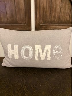 rectangular throw pillow features a light gray linen blend and embroidered white "HOME"