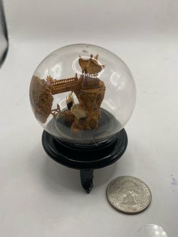 A vintage Chinese hand-carved cork art diorama inside a spherical glass globe on a black wooden stand.