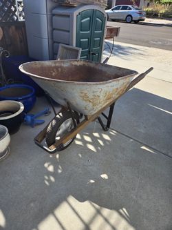 Sturdy metal wheelbarrow with wooden handles.