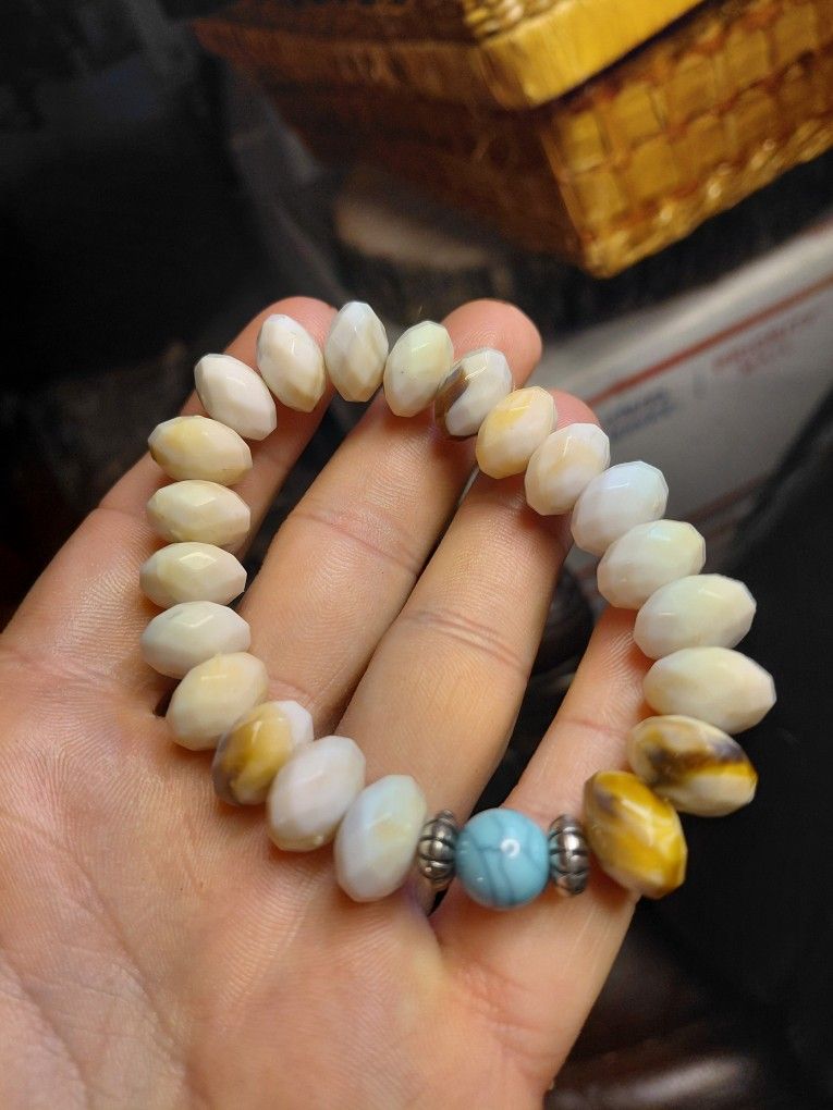 stretch beaded bracelet featuring polished oval-shaped white beads, variegated brown and white jasper beads, a turquoise bead, and silver-tone spacer 