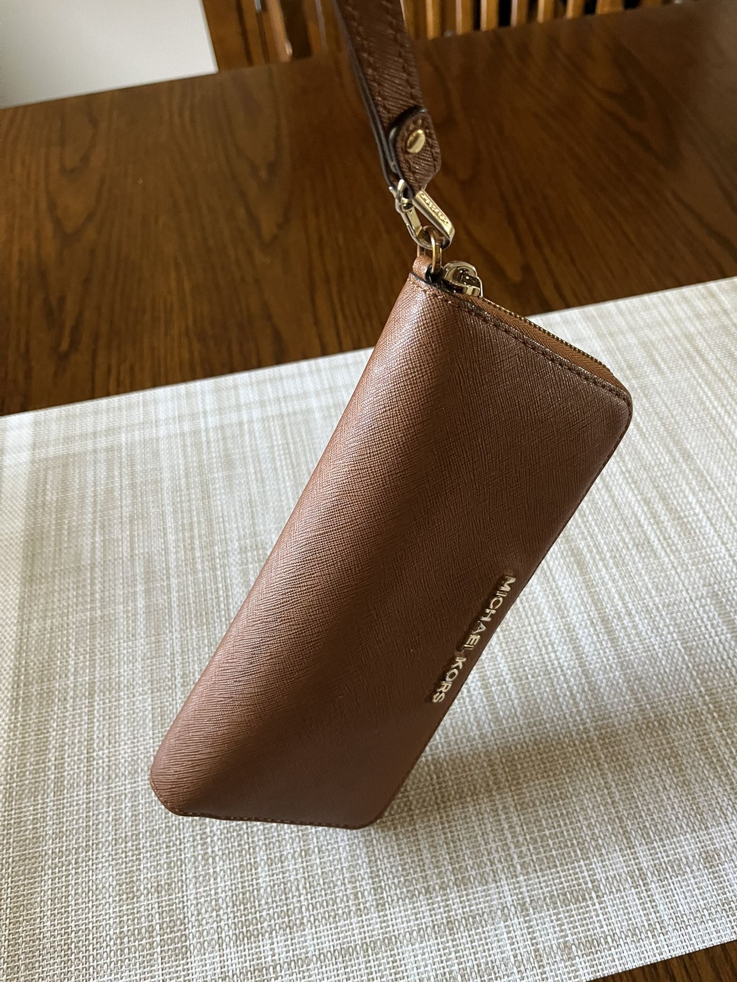 It’s A Michael Kors wristlet wallet the color is brown it is barely used