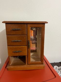 A very beautiful musical jewelry box featuring three drawers, a mirror, and a door with hooks for bracelets or necklaces; it measures 11 inches high, 
