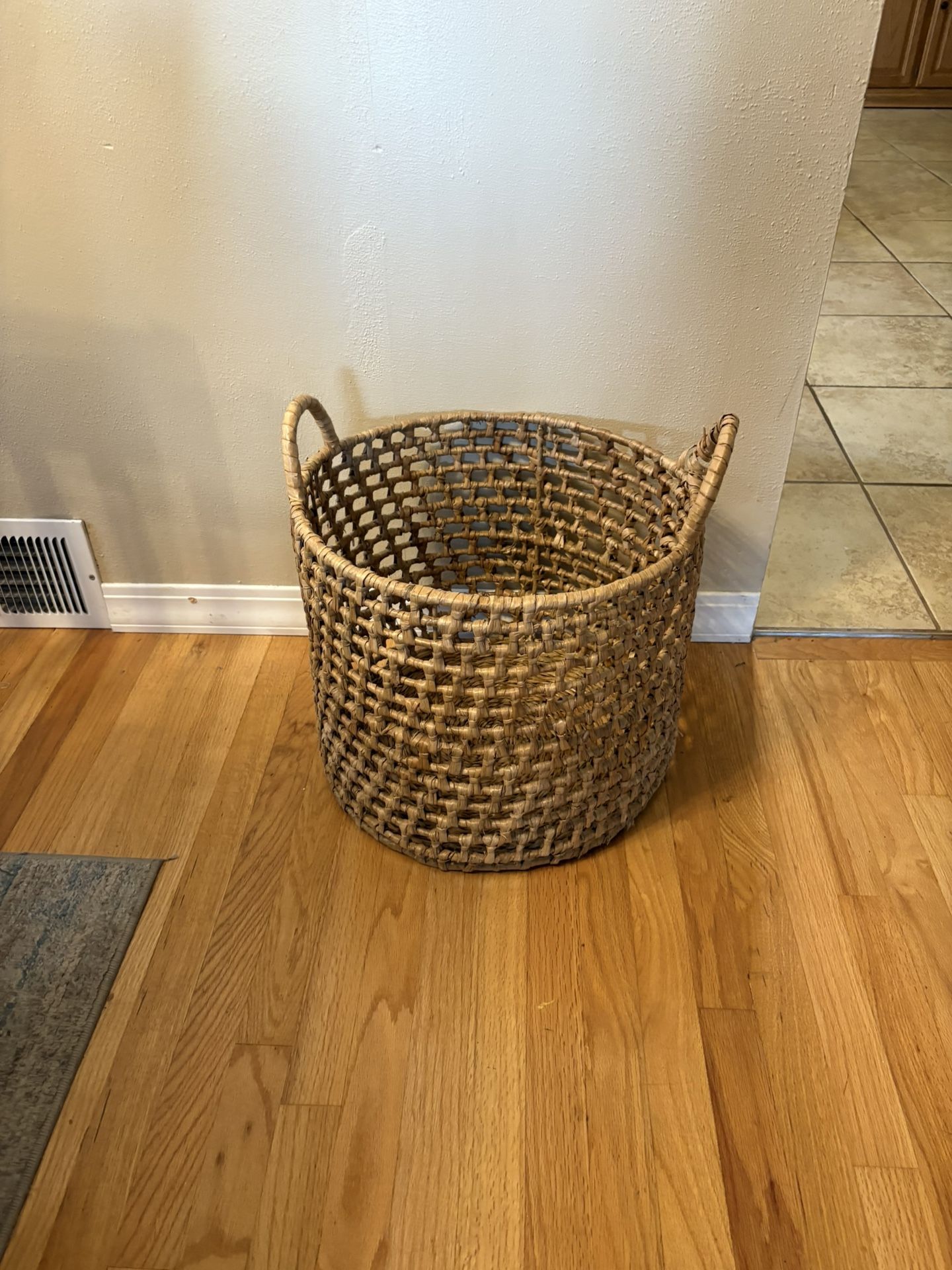 round, open-weave water hyacinth storage basket with handles.