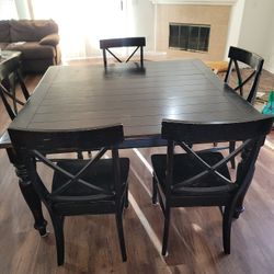 large solid wooden dinner table with five chairs