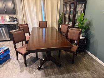 Dark wood dining table with 6 chairs and china