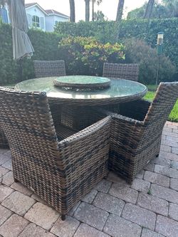 Outdoor dining set with a round glass-top table and 5 matching wicker armchairs 120 or best offer.