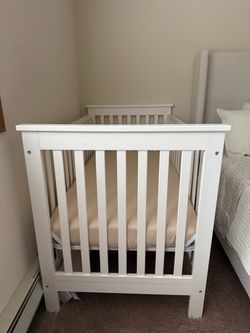 White wooden crib with new mattress