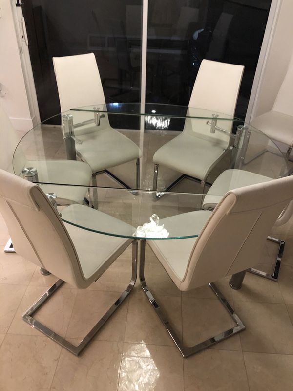 Round glass dining room table with 8 white chairs set in polished